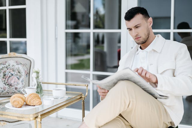 homme-manches-blanches-assis-lit-journal